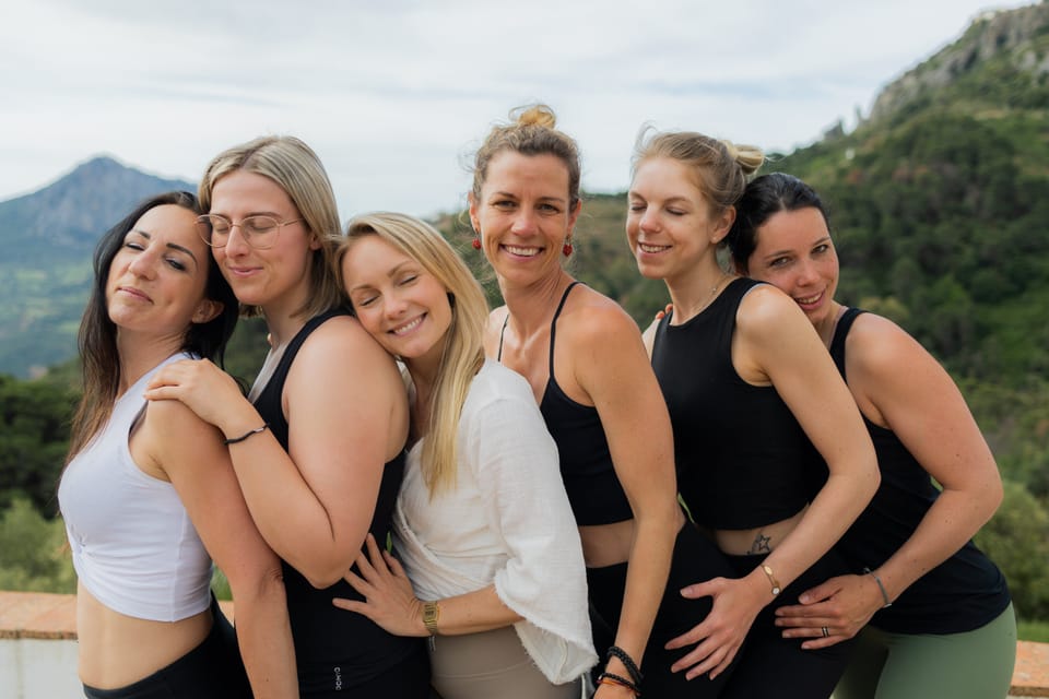 Eine Gruppe von Frauen steht eng beieinander auf einer Terrasse und lacht in die Kamera